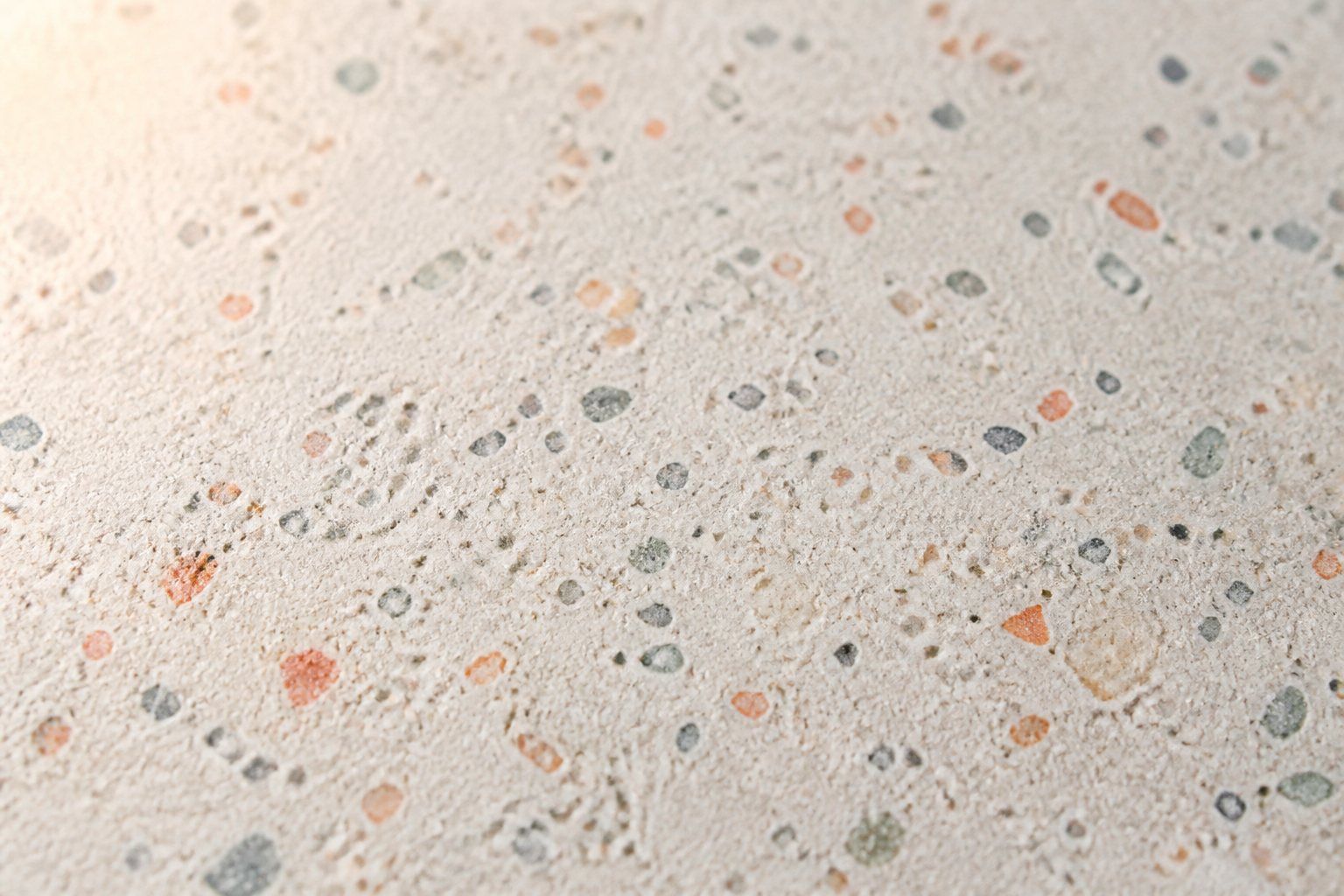 Gros plan d'une surface en Jesmonite mate, mouchetée d'éclats terrazzo terracotta, sauge et gris